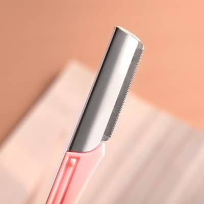 Sharp metal razor with pink handle for skincare grooming and shaving beauty tools.