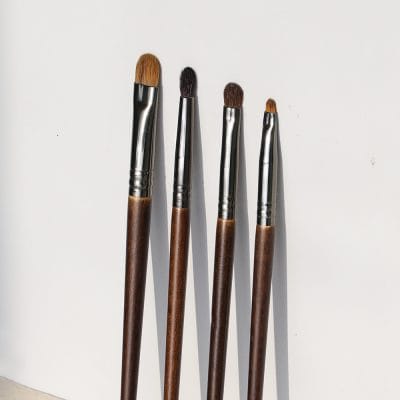 Artistic makeup brushes with wooden handles and silver ferrules, ideal for eye, lip, and face makeup application. Perfect for professional and everyday beauty routines.