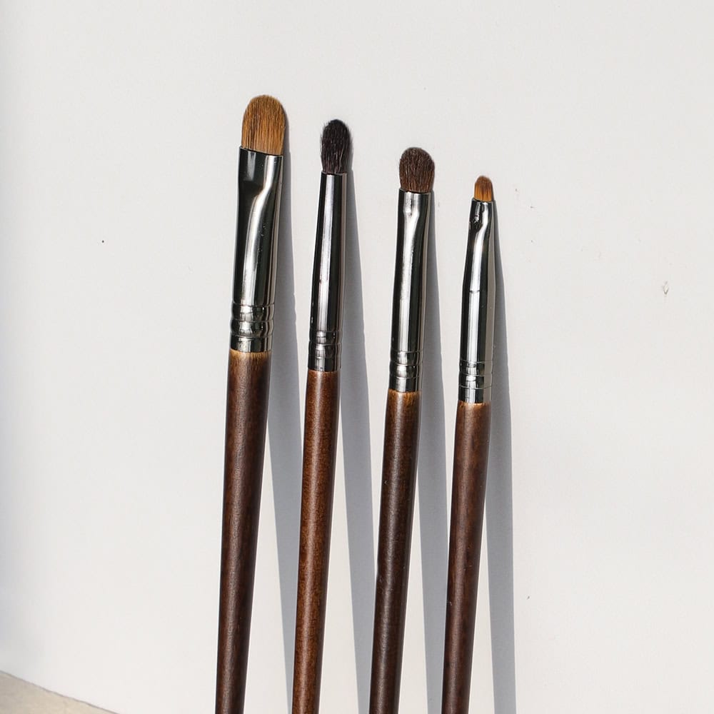 Artistic makeup brushes with wooden handles and silver ferrules, ideal for eye, lip, and face makeup application. Perfect for professional and everyday beauty routines.
