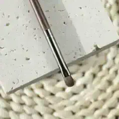 Precision makeup brush on textured stone surface, ideal for flawless application of foundation and concealer, part of Monalisa Store's beauty and cosmetics collection.