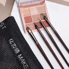 Vegan makeup palette with neutral and warm tones, accompanied by four professional makeup brushes and a black zippable pouch, perfect for beauty enthusiasts and makeup artists.