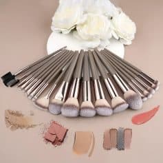 Precision makeup brushes set displayed on beige background with powder, blush, and lipstick swatches for professional cosmetic application.