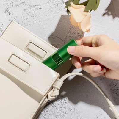 Silicone facial device being placed into a white handbag on a textured surface with a beige flower; skincare essentials, beauty accessories, and luxury beauty products from Monalisa Store.