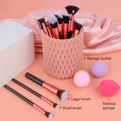 Silicone storage bucket with pink makeup brushes, small brush, lager brush, and makeup sponges on pink background for beauty and makeup organization.