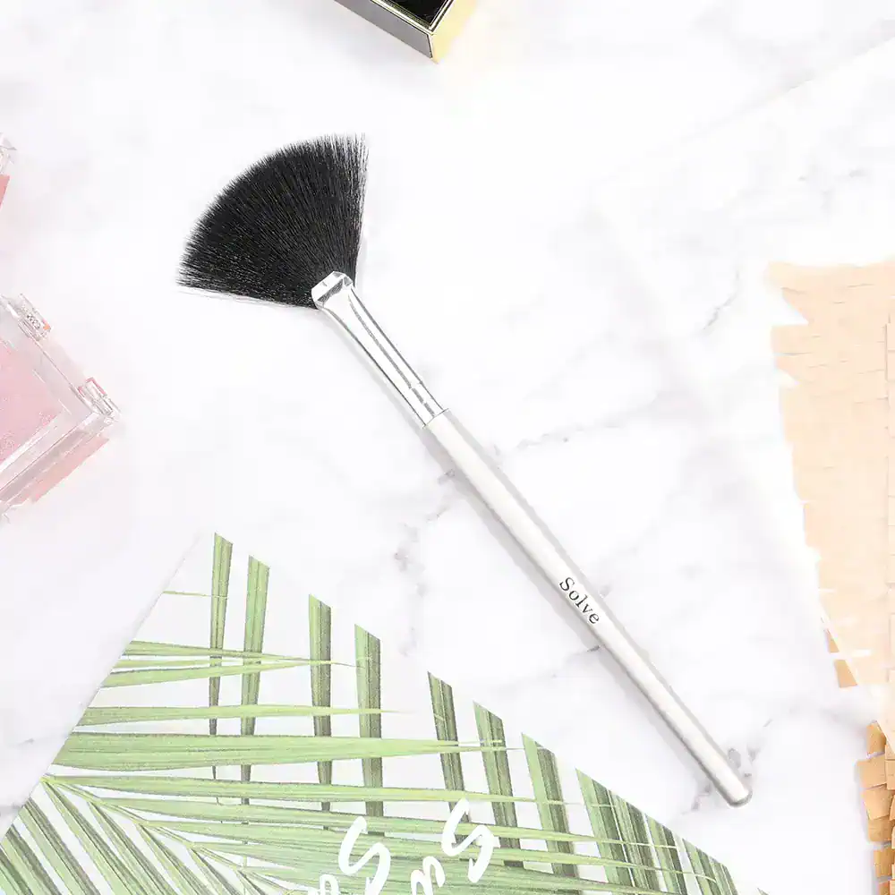 Silk fan makeup brush on marble background with Monalisa Medical Store branding and greenery for elegant beauty and skincare product presentation.