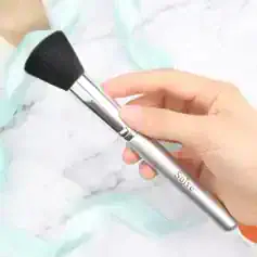 Soft-focus makeup brush with "Solve" branding against marble surface, ideal for beauty and skincare routines.