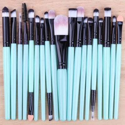 Soft teal makeup brush set with black and white bristles, suitable for face, eyes, and lips, displayed on a wooden surface for professional and personal cosmetic use.