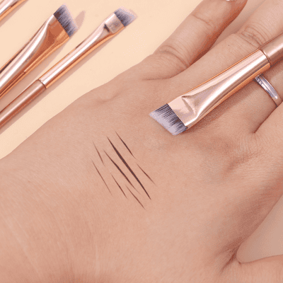 Silky makeup brushes and eye liner swatches displayed on a hand, showcasing professional cosmetic tools from Monalisa Store for beauty and eyelash enhancement.