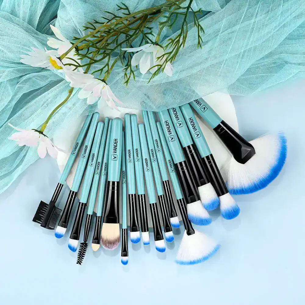 Blue makeup brushes set on white background with flower and tulle decor, ideal for professional cosmetic and beauty salon use, featuring high-quality tools for flawless makeup application.