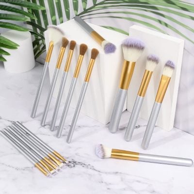 Silicone makeup brush set with gold and silver handles, ideal for skincare and beauty routines, displayed on a marble surface with greenery.