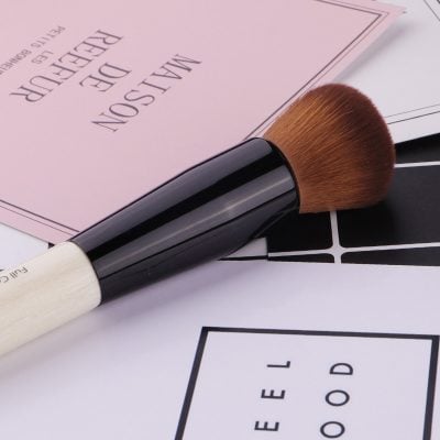 Flawless makeup brush on Monalisa Medical store promotional papers, emphasizing professional cosmetic tools and skincare product essentials.