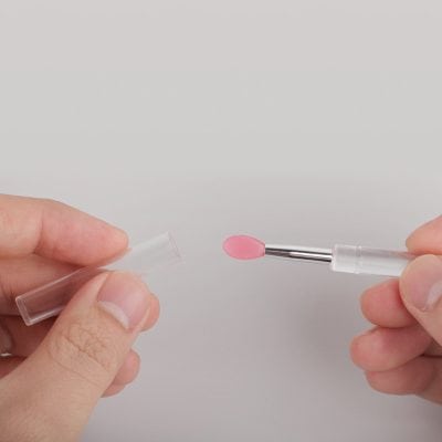 Nail sample collection brush with pink cap, ideal for medical or cosmetic use, displayed on plain background.
