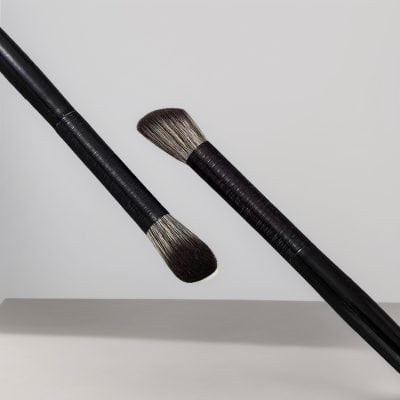 Fluffy makeup brushes with black handles floating against a light gray background for skincare and beauty application.