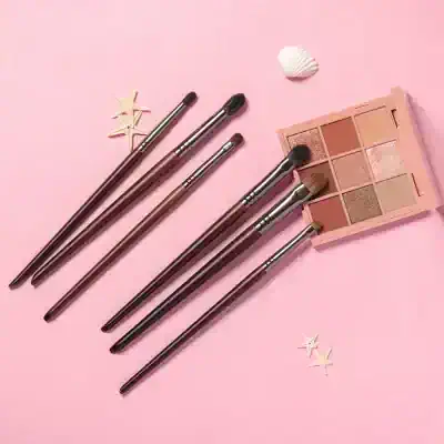 Elegant makeup brushes with eyeshadow palette on pink background, ideal for beauty and cosmetic applications. Perfect for creating professional eye makeup looks at Monalisa Store.