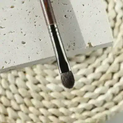 Precision makeup brush close-up on textured surface for professional beauty applications at Monalisa Store, a top destination for high-quality cosmetics and skincare products.