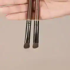 High-quality makeup brushes held by hand, ideal for professional cosmetic application, beauty products, and skincare routines. Perfect for achieving flawless makeup looks.