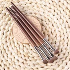 Soft brown makeup brushes with wooden handles arranged on a woven straw surface for skincare, beauty, and cosmetic application. Ideal for professional and personal makeup use from Monalisa Store.