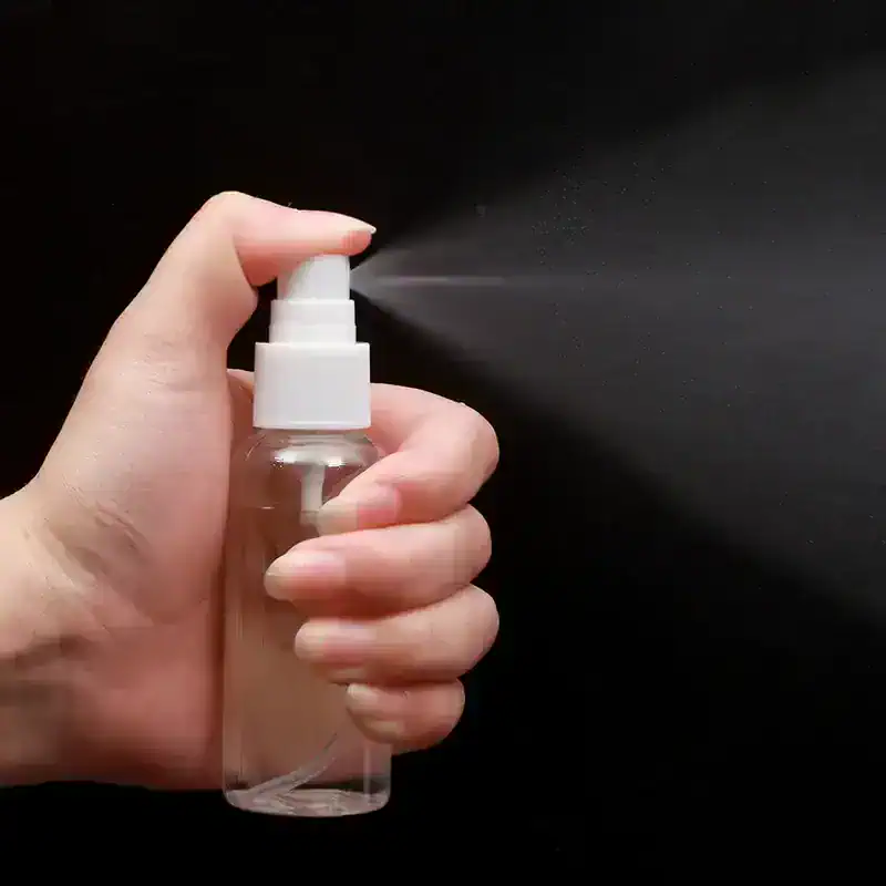 Moisturizer spray bottle with mist being sprayed onto a black background, suitable for skincare and cosmetic use.