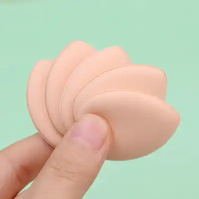 Soft silicone makeup sponges in a peach color, ideal for foundation blending and skincare application, displayed held by a hand against a pastel green background.