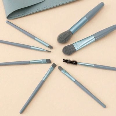 Brush set for professional makeup application and cosmetics, including eye, face, and eyebrow brushes, on beige surface at Monalisa Store.