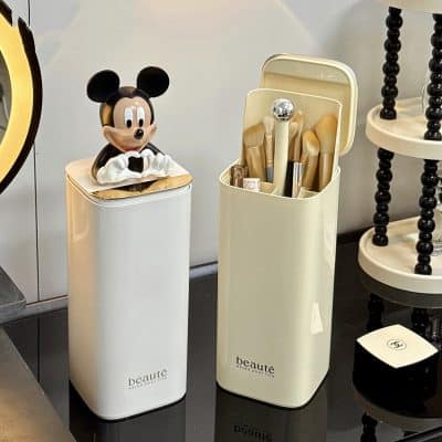 Miniature Mickey Mouse figurine on a sleek white cosmetic container, showcasing stylish beauty and makeup storage solutions; ideal for beauty aficionados and interior decor.