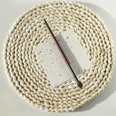Natural stone sample with makeup brush on woven placemat for beauty and skincare aesthetic.