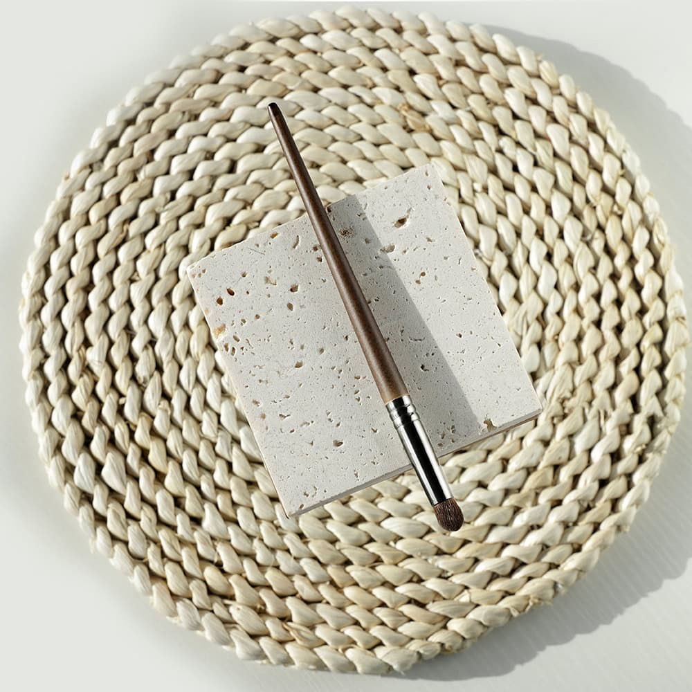 Luxurious beige woven placemat with a white porous ceramic tile and a brown makeup brush on top, perfect for beauty and skincare product display at Monalisa Store.