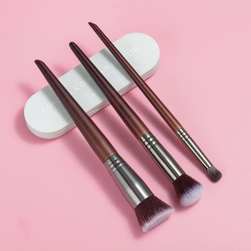 Soft brown makeup brushes with synthetic bristles on pink background.