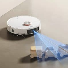 Autonomous robot vacuum cleaner with laser navigation cleaning small wooden toy cars on beige floor, illustrating smart home cleaning technology and robotic floor sweepers.