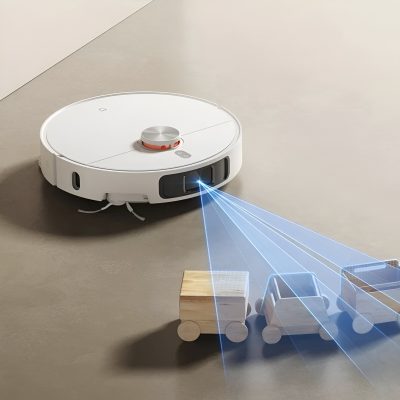 Autonomous robot vacuum cleaner with laser navigation cleaning small wooden toy cars on beige floor, illustrating smart home cleaning technology and robotic floor sweepers.