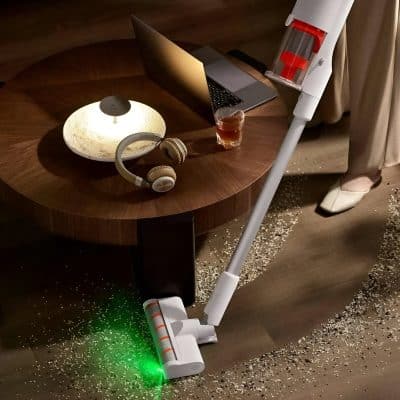 Vacuum cleaner on wooden floor, cleaning scattered rice, modern home cleaning device, cordless stick vacuum, household cleaning tools for everyday messes.