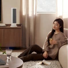 Relaxing woman enjoying air purifier at home, cozy living room, modern air cleaner, fresh air environment, healthy home air quality, comfortable interior, peaceful lifestyle, indoor air purification, Monalisa Store.