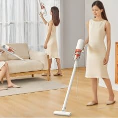 Vacuuming a living room with modern stick vacuum cleaner, demonstrating home cleaning with cordless device, cozy interior, and minimalist design.