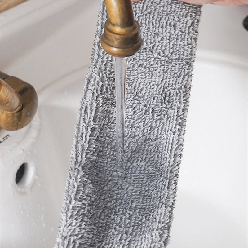 Soft gray microfiber towel hanging under a running faucet in a bathroom sink, emphasizing cleanliness and hygiene.