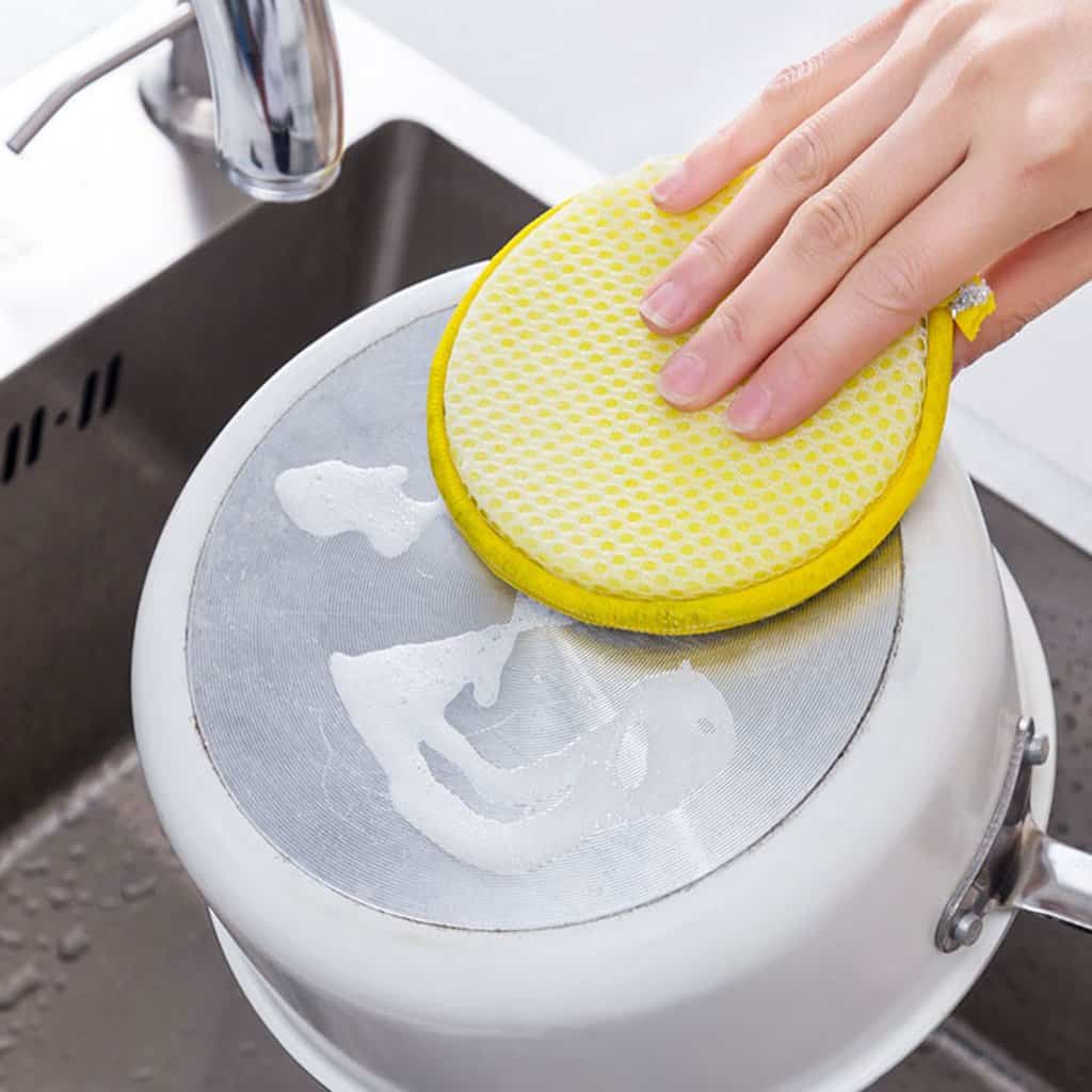 Kitchen cleaning sponge scrubbing a pot in a sink for hygienic kitchen cleaning and maintenance.