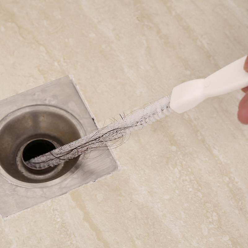 Clogged drain hair removal tool in bathroom, cleaning drain pipe with wire brush.