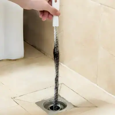 Flexible drain snake cleaning tool for unclogging kitchen or bathroom drains, easy to use for plumbing maintenance.
