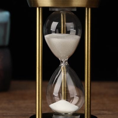 Black and gold hourglass with white sand, representing time management and precision in healthcare services.