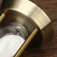 Shaker with salt and pepper in a gold holder on a wooden table at Monalisa Store, specializing in optical products and accessories.