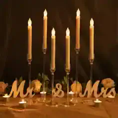 Elegantly lit candles for wedding decor centerpiece with "Mr & Mrs" sign, surrounded by white roses, creating a romantic and warm ambiance for special occasions and celebrations.