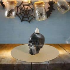 Skull-shaped candle holder with a white candle on top, Halloween-themed Halloween decor, spooky ambiance, black and white candle, decorative skull for Halloween parties.
