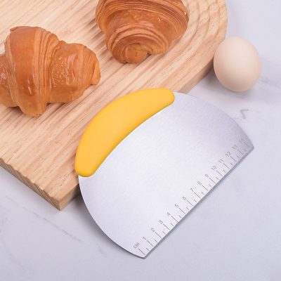 Butter knife cutting butter on a food scale with croissants and an egg on a wooden cutting board.