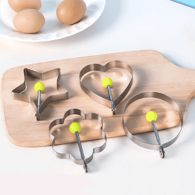 Stainless steel cookie cutters in star, heart, flower, and circle shapes with yellow handles on a wooden cutting board for baking and kitchen use.