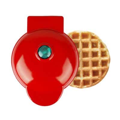 Red waffle maker with batter waffle beside it for breakfast or dessert recipes, kitchen appliance for making golden brown waffles.