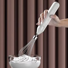 Whisk attachment being used in a kitchen setting, blending ingredients in a glass bowl; modern electric hand mixer for baking and cooking.