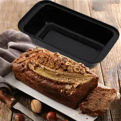 Cakes in a baking container, banana bread with chopped nuts, on a rustic wooden table.