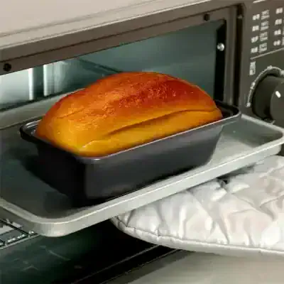 Freshly baked golden bread loaf inside an oven, cooling on a baking tray.