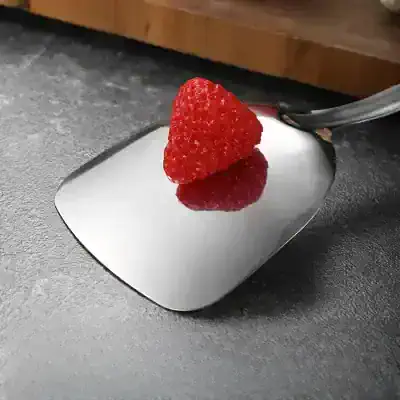 Fresh red raspberry on reflective kitchen scale for precise weight measurement, ideal for healthy eating and dietary tracking.