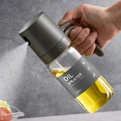 Oil spray bottle for kitchen use, cooking, or food preparation, with a modern gray design and transparent container showing yellow oil, ideal for kitchen conveniences, health, and cooking tools, Monalisa Store.