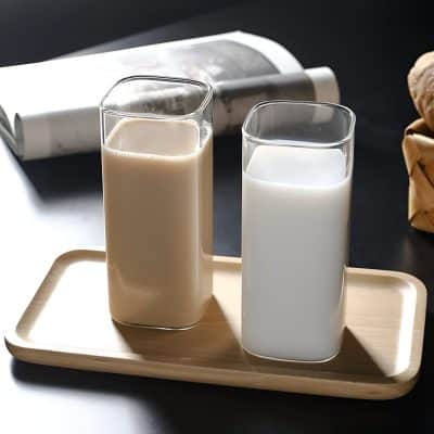Creamy and plain milk in stylish square glass bottles on a wooden tray showcasing dairy beverages at Monalisa Store.